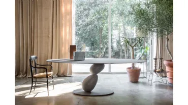 Tavolo ovale con struttura in metallo e piano in MDF rivestito con finiture materiche con due sassi che sorreggono il piano Matera di Mogg